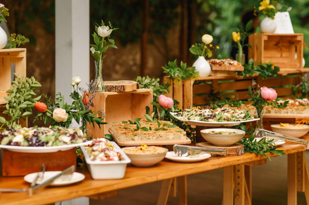 buffet food for party decorated with fresh plants.